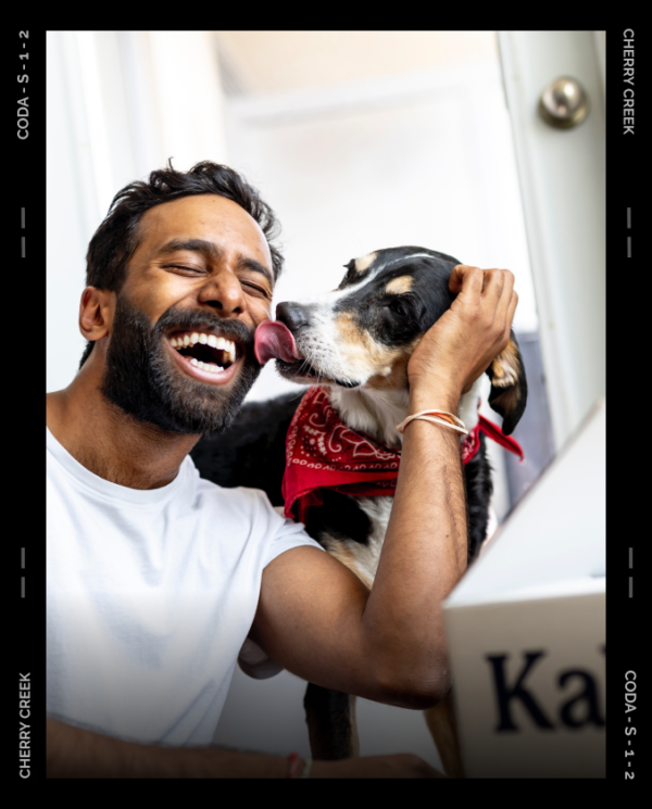 Person smiling while dog licks their face.