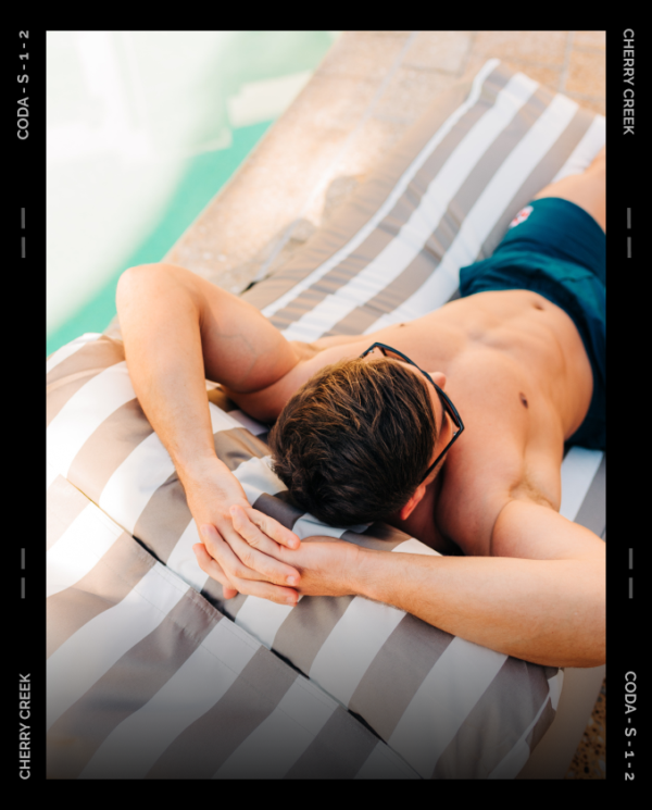 Person relaxing on chair next to pool.
