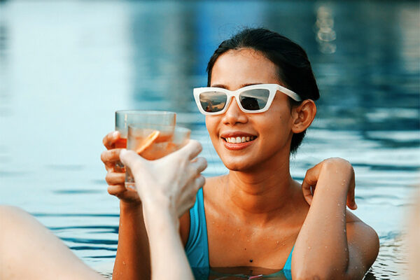 People toasting with cocktails standing in pool.